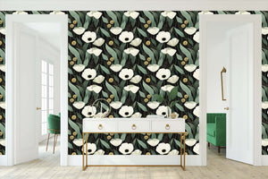 Gilded Night Botanicals Wallpaper with white flowers, sage leaves, and gold accents on a black background in a modern room setting.