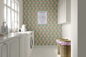 Retro atomic windowpane wallpaper in mint green, cream, and coral lines, showcasing mid-century modern geometric design in a laundry room.